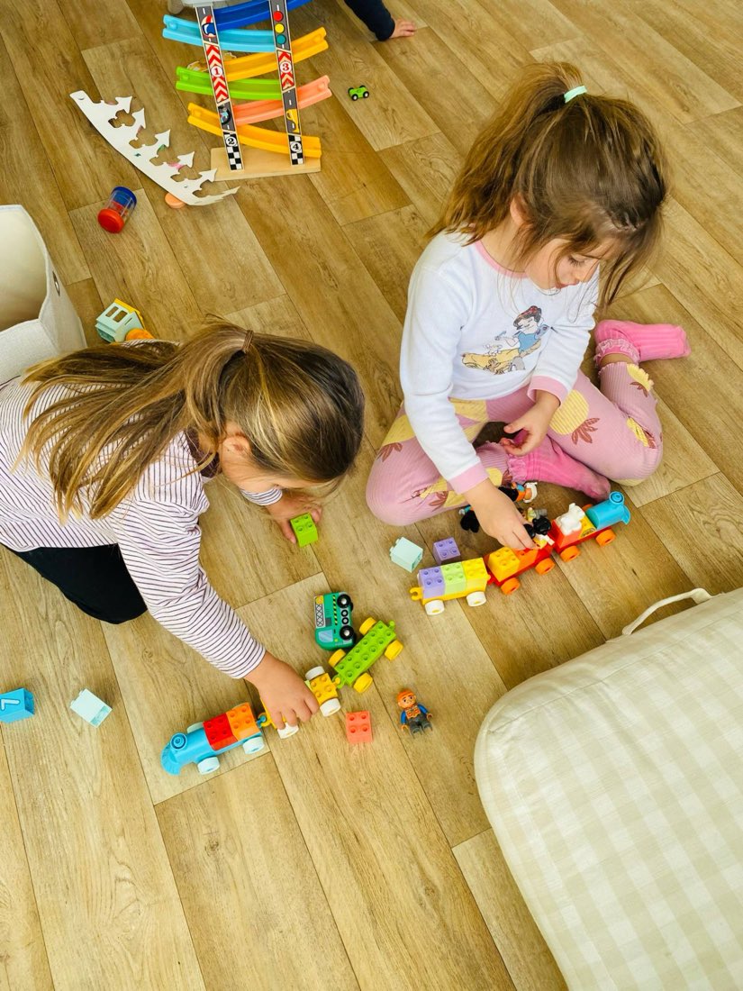 Two girls building trains with blocks on the studio floor