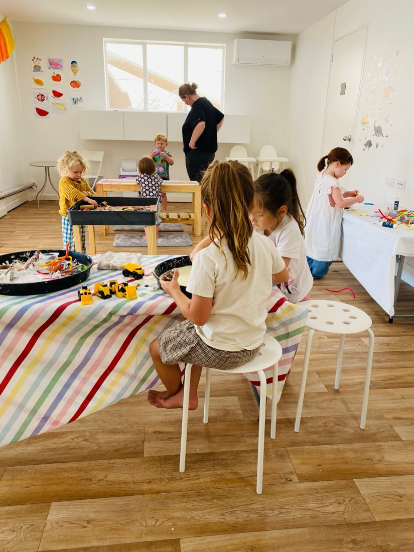 Children busy at different activity tables around the bright studio