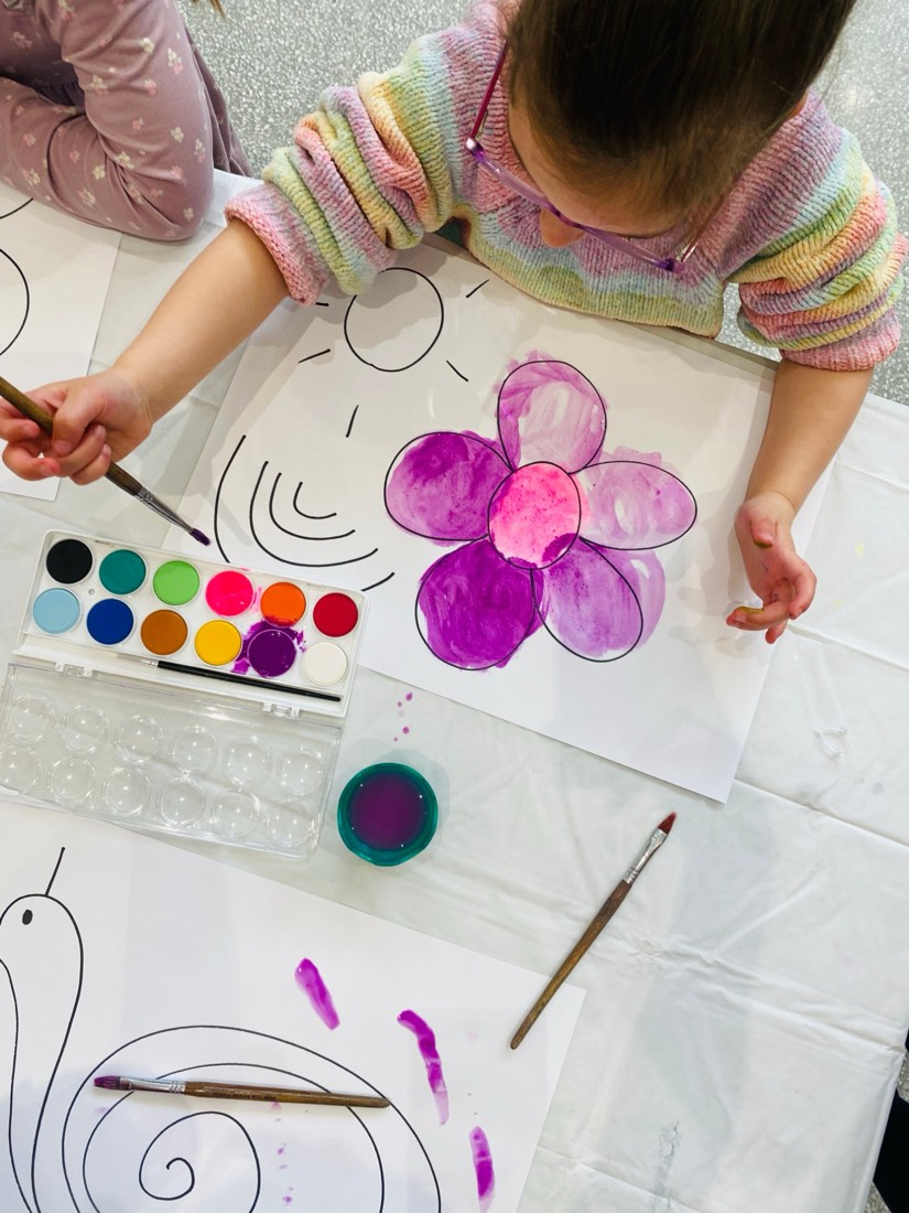 Child painting a watercolour flower at the studio