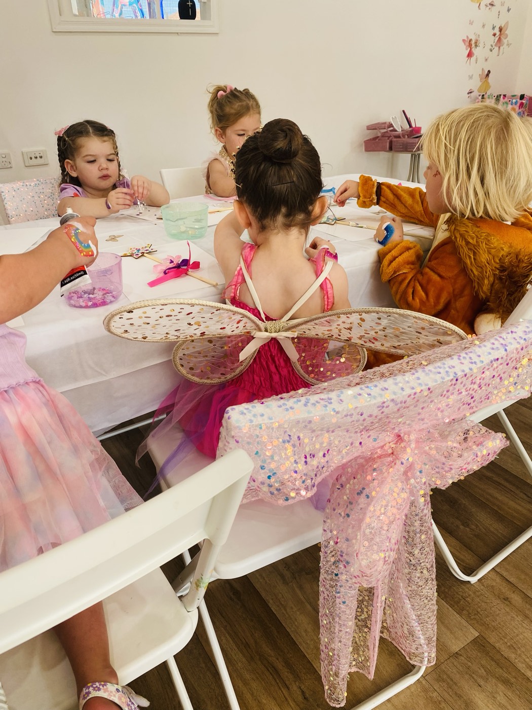 Children in fairy wings crafting at the party table