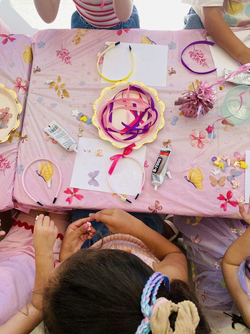 Pink party table covered in headband decorating supplies