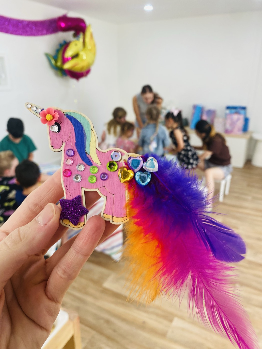A decorated wooden unicorn and a room full of party guests