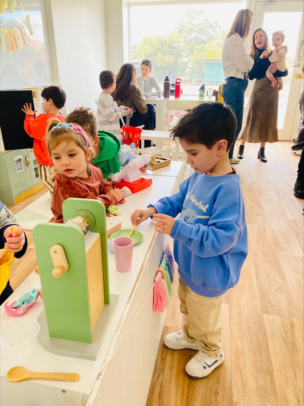 Children playing shops while parents chat in the background