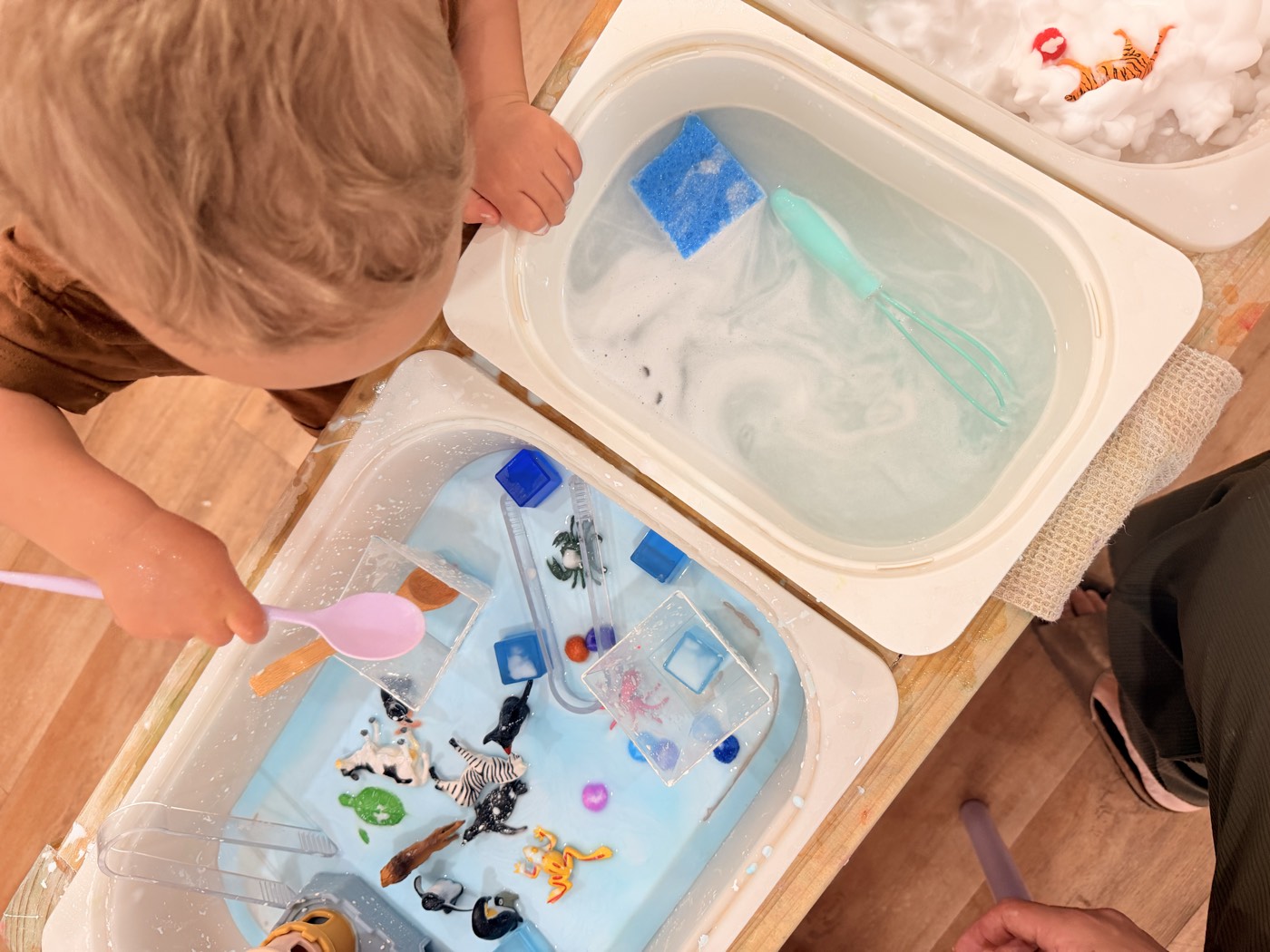 Children playing in water trays at a messy play session